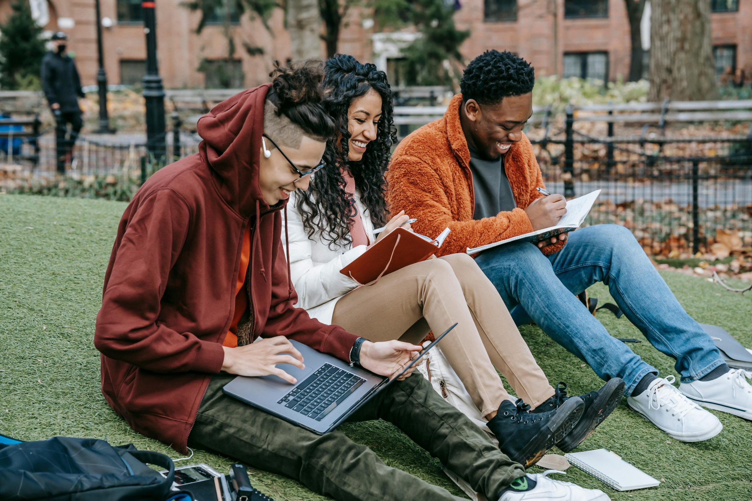 Students studying and taking notes on a campus lawn