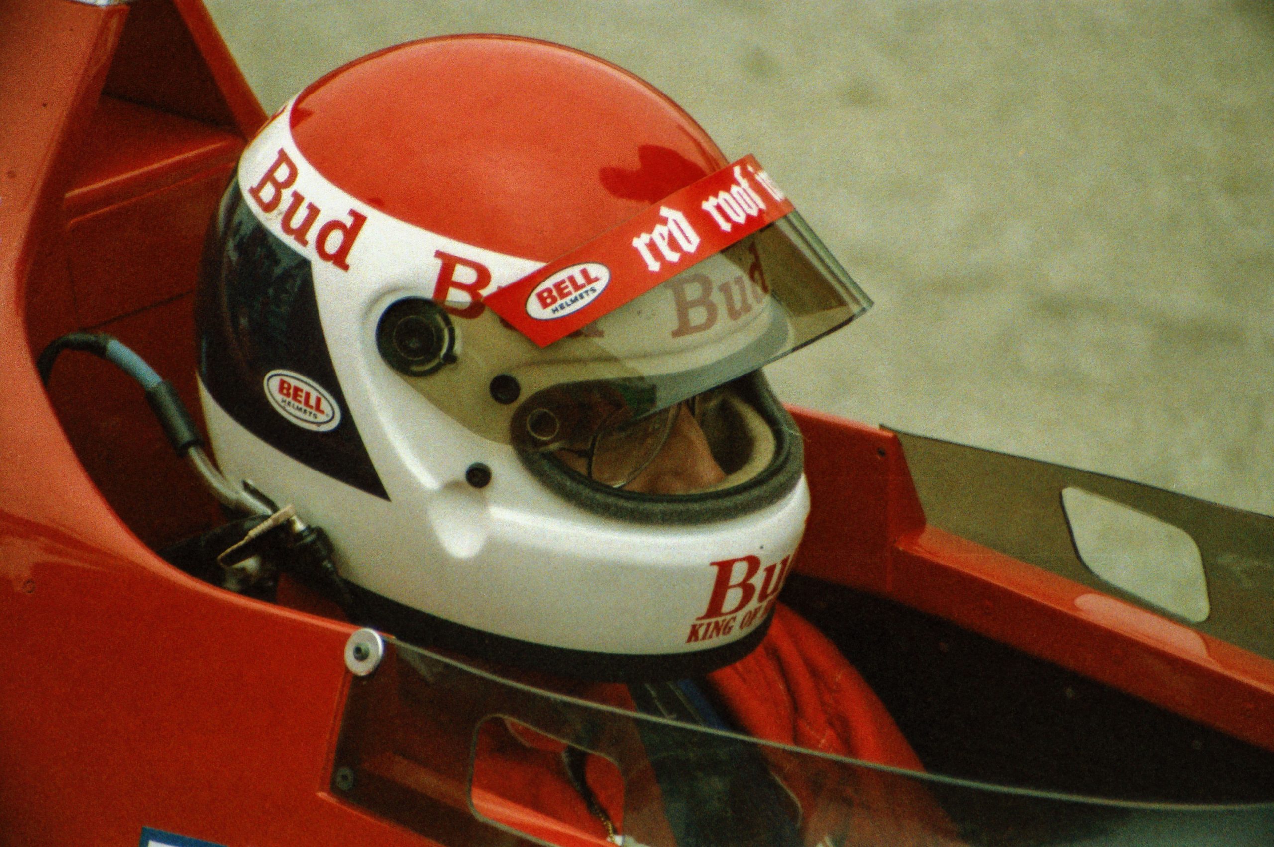 Close-up of a driver's red and white racing helmet with sponsor decals